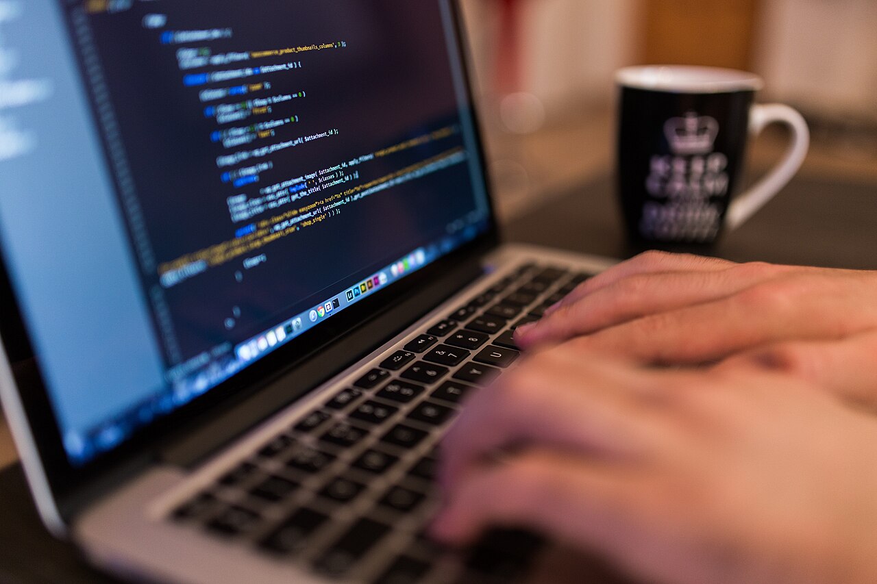 Hands typing code on a Mac laptop.